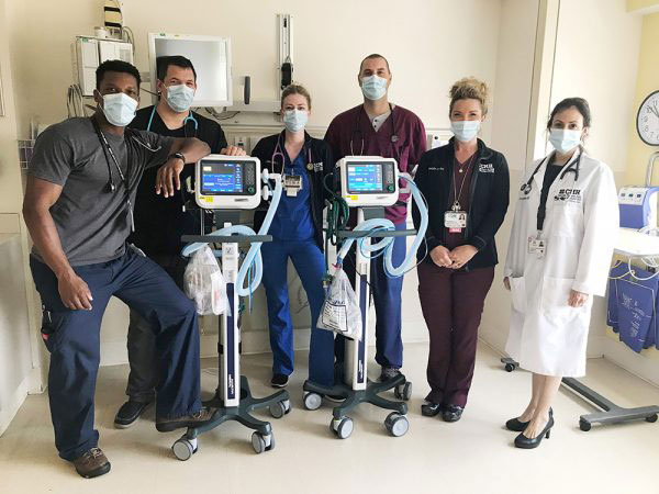People in masks standing with medical equipment
